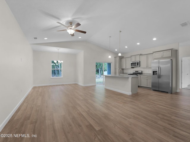 kitchen featuring gray cabinets, pendant lighting, a center island with sink, appliances with stainless steel finishes, and ceiling fan with notable chandelier