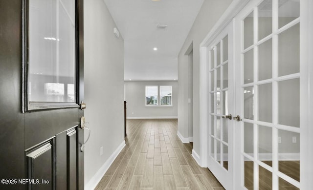 hall with french doors and light wood-type flooring