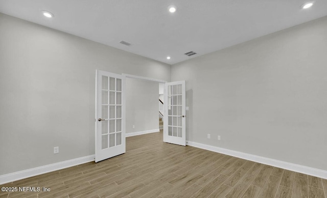 spare room featuring french doors and light hardwood / wood-style flooring