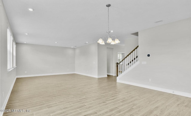 spare room with a notable chandelier and light hardwood / wood-style flooring