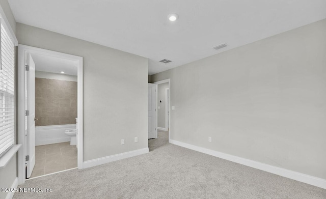 unfurnished bedroom with connected bathroom and light carpet