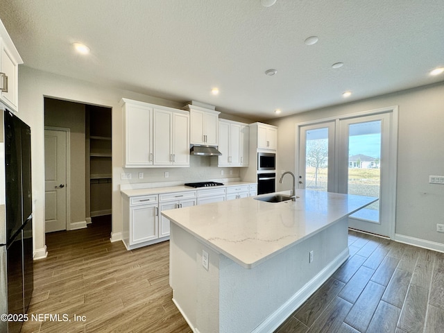 kitchen featuring white cabinetry, sink, a center island with sink, and black appliances