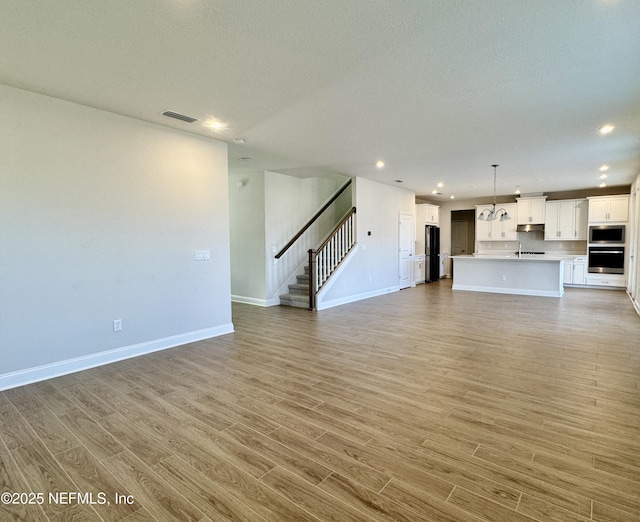 unfurnished living room featuring a textured ceiling and light wood-type flooring