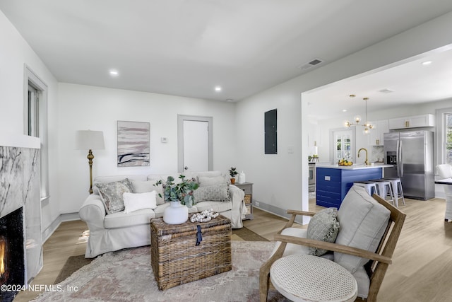 living room featuring electric panel, a fireplace, light hardwood / wood-style floors, and sink