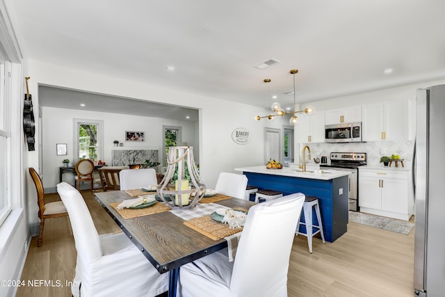 dining space featuring sink, a chandelier, and light wood-type flooring