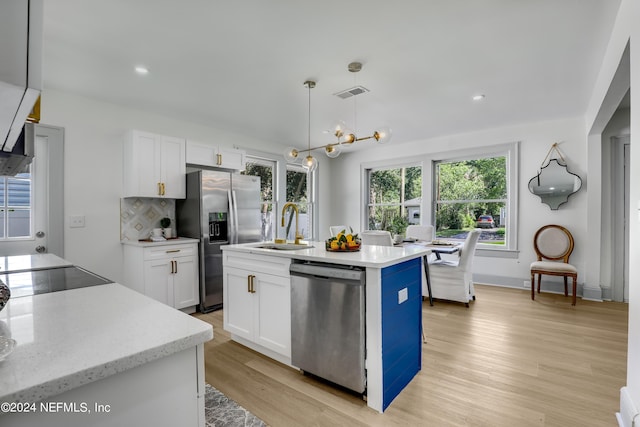 kitchen featuring decorative light fixtures, white cabinets, light hardwood / wood-style flooring, a center island with sink, and appliances with stainless steel finishes