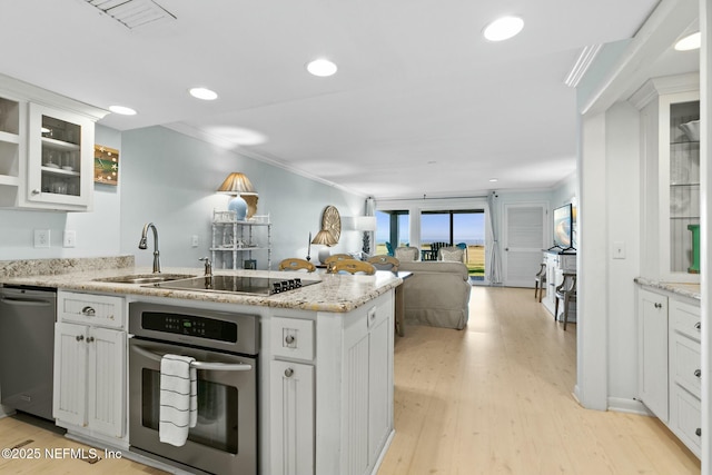 kitchen featuring sink, white cabinets, light wood-type flooring, crown molding, and appliances with stainless steel finishes