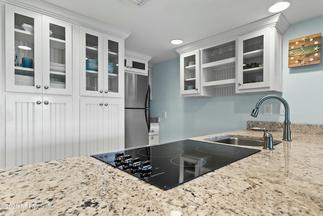 kitchen featuring white cabinetry, light stone countertops, stainless steel fridge, and sink