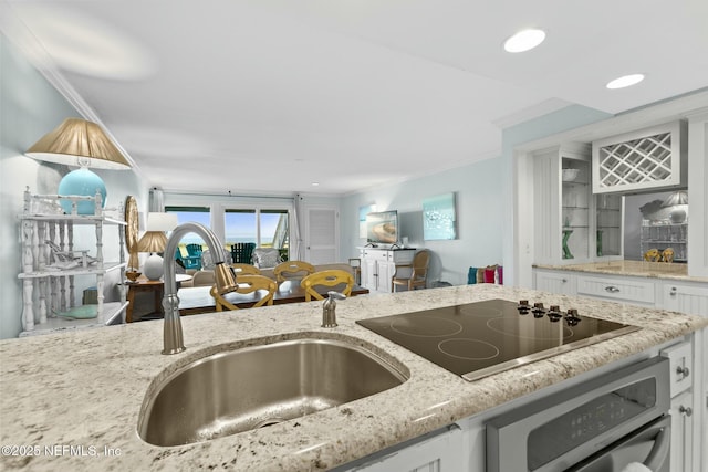 kitchen with sink, oven, white cabinetry, and black electric cooktop