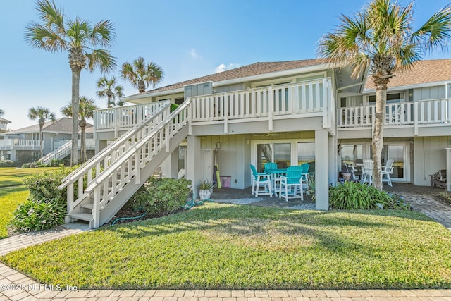 back of house with a yard, a wooden deck, and a patio