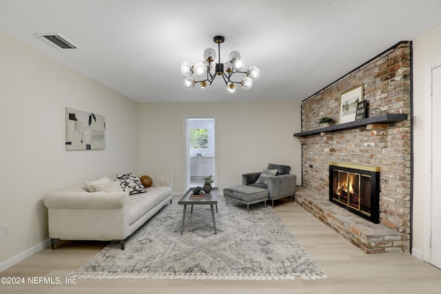 living room with a brick fireplace, light wood-type flooring, and a notable chandelier