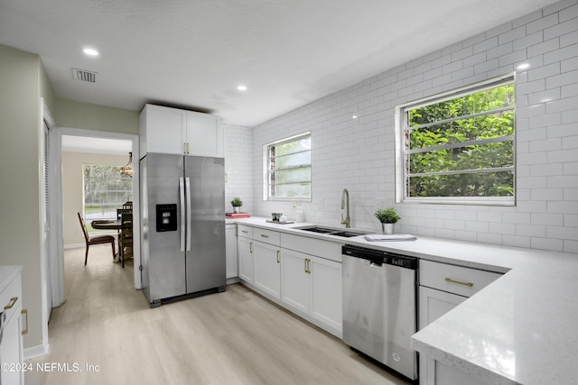 kitchen featuring stainless steel appliances, white cabinetry, sink, and backsplash