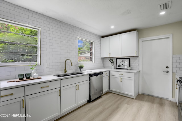 kitchen featuring dishwasher, light wood-type flooring, sink, white cabinetry, and backsplash