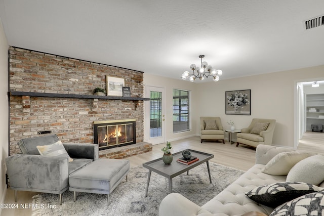 living room with a notable chandelier, light hardwood / wood-style floors, and a brick fireplace