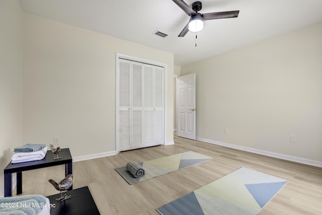 workout area featuring light wood-type flooring and ceiling fan