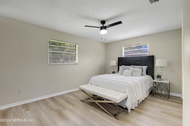 bedroom featuring multiple windows, ceiling fan, and light hardwood / wood-style flooring