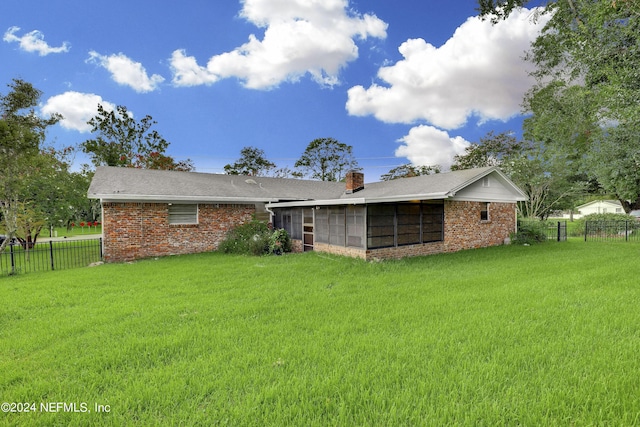 rear view of property with a yard and a sunroom