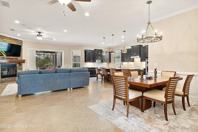 dining space featuring light tile patterned flooring, crown molding, and a fireplace