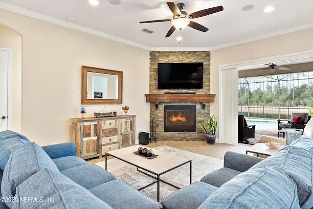 living room featuring ornamental molding, ceiling fan, a fireplace, and light tile patterned floors