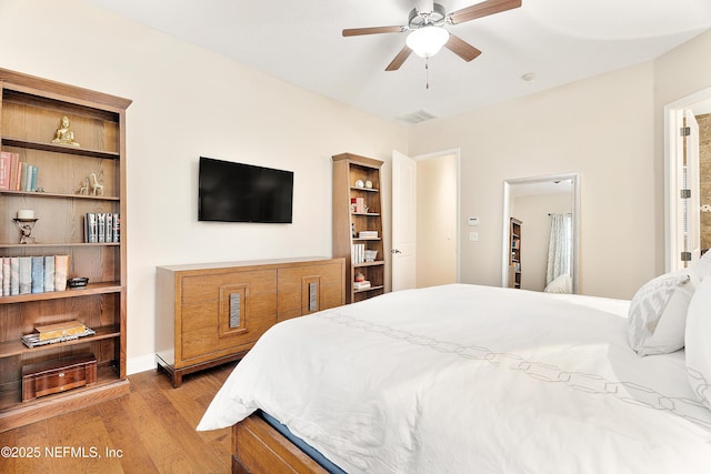 bedroom featuring a spacious closet, ceiling fan, and light hardwood / wood-style flooring