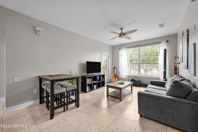 tiled living room featuring ceiling fan and a textured ceiling