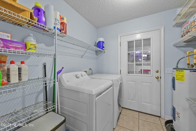 laundry area with water heater, a textured ceiling, separate washer and dryer, and light tile patterned floors