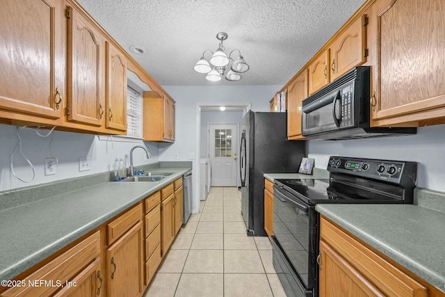 kitchen with black appliances, light tile patterned floors, an inviting chandelier, washing machine and clothes dryer, and sink