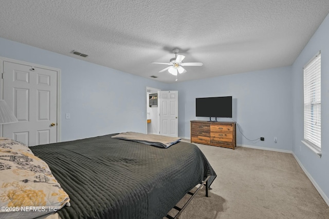 carpeted bedroom featuring multiple windows, a textured ceiling, and ceiling fan