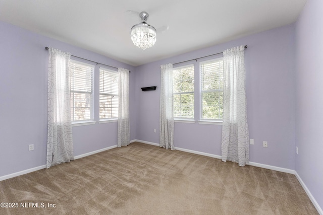 carpeted empty room featuring an inviting chandelier