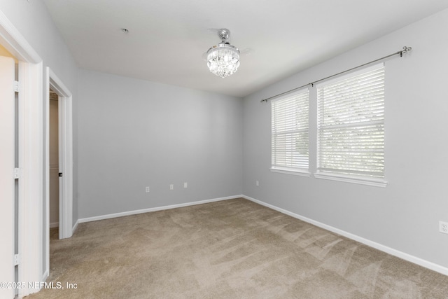 unfurnished bedroom with light colored carpet and a chandelier