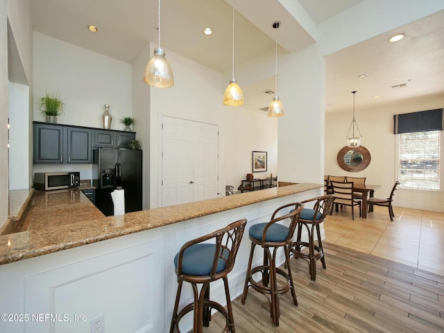 kitchen featuring black refrigerator with ice dispenser, pendant lighting, gray cabinetry, and kitchen peninsula