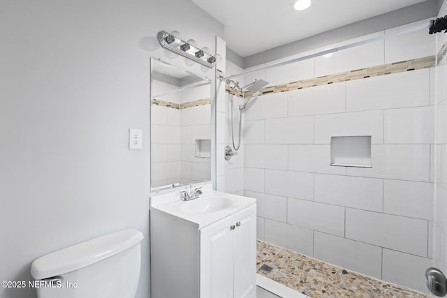 bathroom with toilet, vanity, and a tile shower