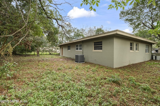 view of side of home featuring central AC unit and a yard