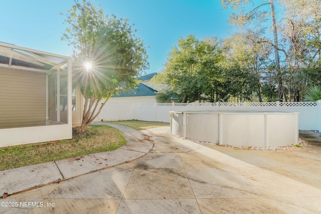 view of yard featuring glass enclosure, a fenced in pool, and a patio area