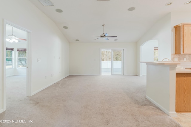 unfurnished living room with ceiling fan, a healthy amount of sunlight, and light carpet