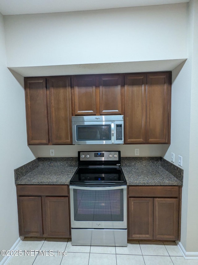 kitchen featuring stainless steel appliances, light tile patterned floors, and dark brown cabinetry