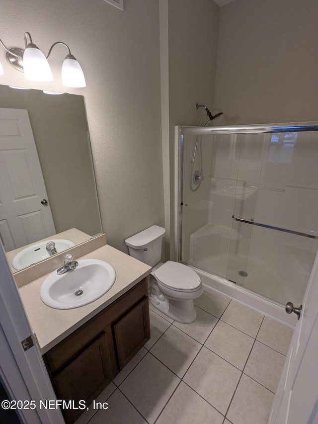 bathroom with vanity, tile patterned flooring, a shower with shower door, and toilet