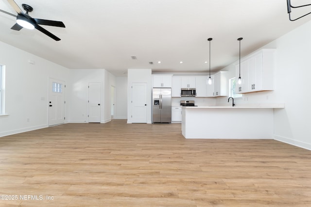 kitchen with pendant lighting, white cabinetry, stainless steel appliances, and light wood-type flooring