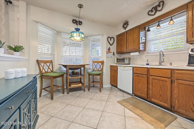 kitchen featuring pendant lighting, light tile patterned floors, white dishwasher, and plenty of natural light