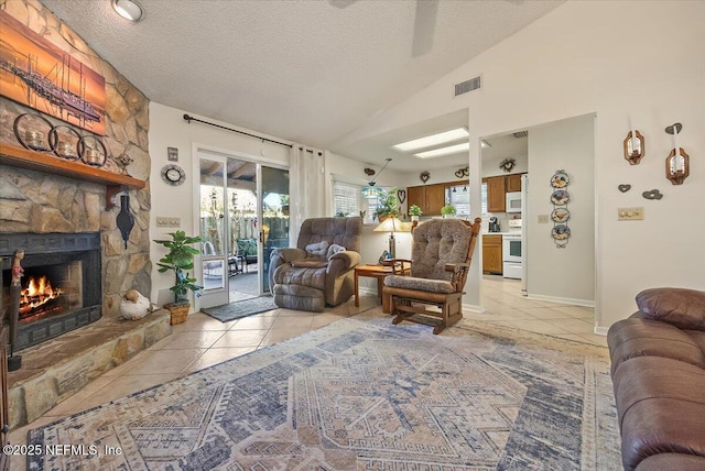 living room featuring a stone fireplace, light tile patterned floors, a textured ceiling, and lofted ceiling