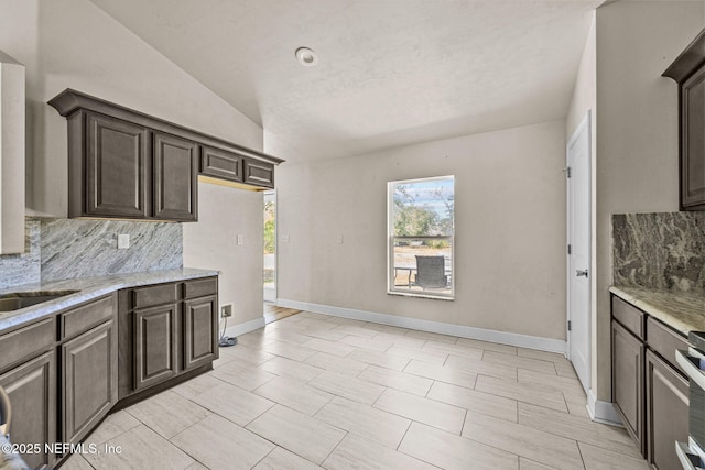 kitchen with tasteful backsplash, light stone countertops, and dark brown cabinets