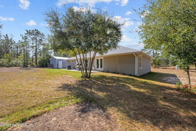 exterior space featuring french doors, a patio, a shed, and a lawn