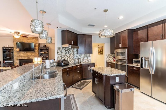 kitchen featuring sink, stainless steel appliances, a center island, and decorative light fixtures