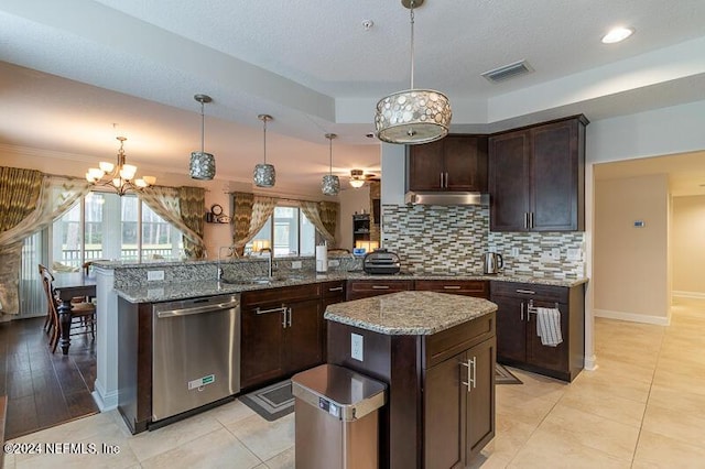 kitchen with kitchen peninsula, stainless steel dishwasher, pendant lighting, a kitchen island, and an inviting chandelier