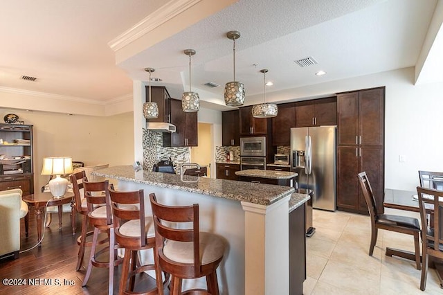 kitchen with appliances with stainless steel finishes, tasteful backsplash, and a breakfast bar