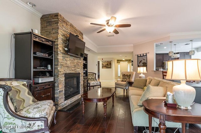 living room with a textured ceiling, dark hardwood / wood-style flooring, a stone fireplace, ornamental molding, and ceiling fan