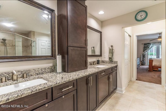 bathroom featuring a shower with shower door, ceiling fan, and vanity