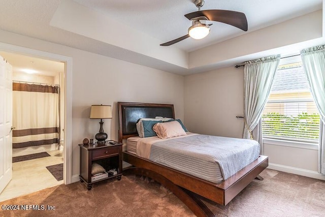 carpeted bedroom with ceiling fan and a tray ceiling