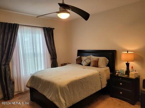 carpeted bedroom featuring ceiling fan and multiple windows