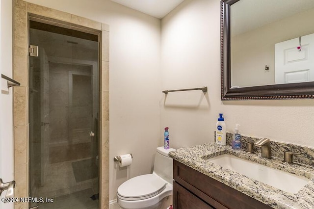 bathroom with toilet, a shower with shower door, and vanity